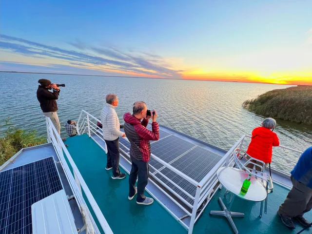 Vogelbeobachter auf dem Sonnendeck des Ibis Tours Hotelschiffs bei Sonnenuntergang